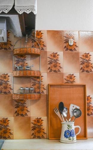 a kitchen with a tile wall with utensils in a vase at Anoi Traditional House Patmos Architectural Charm in Patmos