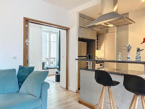 un salon avec un canapé bleu et une cuisine dans l'établissement Appartement contemporain au cœur de Paris, à Paris