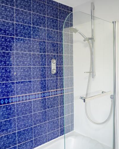 a bathroom with a shower with blue tiles at Rent Entire Calmhaven Apartment in Nottingham