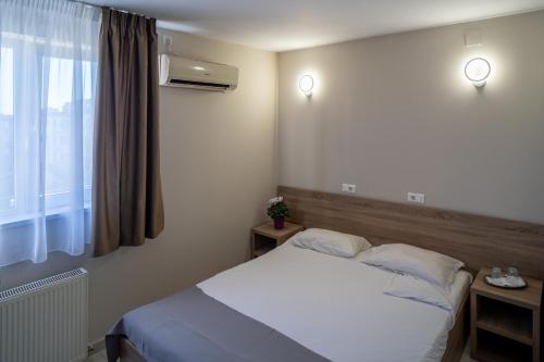 a bedroom with a white bed and a window at City Hotel Bucharest in Bucharest