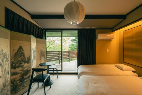 a bedroom with two beds and a table and a window at AKNOT hakone 大涌谷を望むモダニズム建築 東京から90分 in Hakone