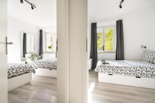 ミュンヘンにあるApartment an der Theresienwieseの白いベッドルーム(ベッド2台、窓2つ付)が備わります。