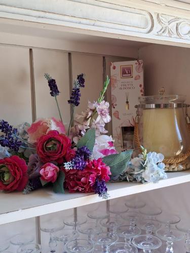 a shelf with flowers and a clock on it at PROVINCIALE 79 in Magreglio