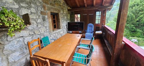 a wooden table and chairs on a balcony with a television at Finca la Vegacha casa tradicional pasiega in San Roque de Ríomiera