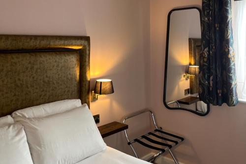 a bedroom with a bed and a mirror and a chair at The Elizabeth House Hotel in Southampton