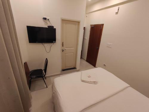 a room with a bed and a tv on the wall at MITRA Hotels & Retreat in Mysore