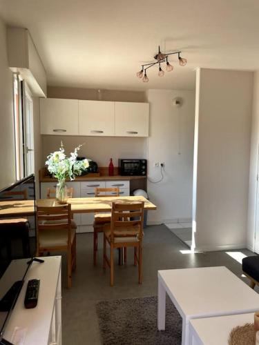 une cuisine avec une table et des chaises et une cuisine avec des armoires blanches dans l'établissement Cosy studio proche Port et Centre ville, à Vannes