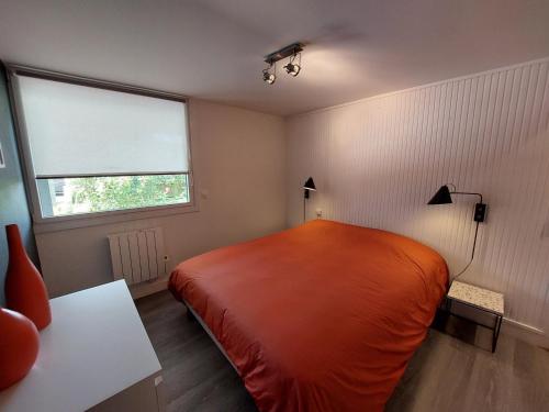 une chambre avec un lit orange et une fenêtre dans l'établissement Charmant T2 près de la plage à Pontaillac - FR-1-550-77, à Royan