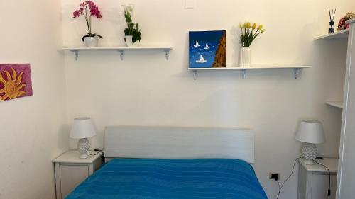 a bedroom with a bed with blue sheets and shelves at CELESTE Central Apartment in Porto Rotondo with private parking in Porto Rotondo