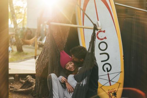 two children sitting in a swing at a playground at Klimatyzowane Surf Domki - Maszoperia Sun4Hel - Letnia Baza SnowShow na Półwyspie Helskim in Jastarnia