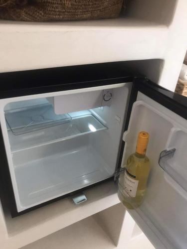 an open refrigerator with a bottle of wine in it at Darsi suites Kythnos in Kithnos