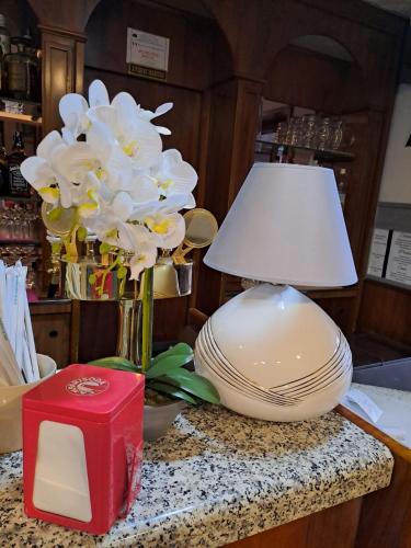 a table with a vase of flowers and a lamp at PROVINCIALE 79 in Magreglio