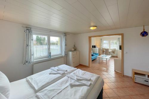 een slaapkamer met een wit bed en een woonkamer bij Haus Antje Gartenbungalow in Kolpinsee