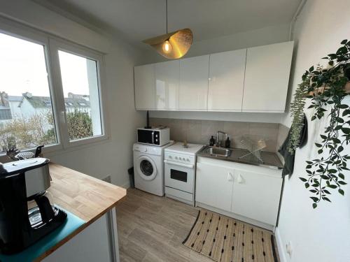 une cuisine avec des armoires blanches et une laveuse et une sécheuse dans l'établissement T1 - parking - 4min de l'intramuros - linge inclus, à Vannes