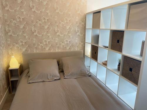 - un lit avec deux oreillers dans une chambre avec des étagères dans l'établissement T1 - parking - 4min de l'intramuros - linge inclus, à Vannes