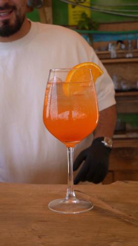 a glass with an orange drink with an orange slice at Badolina Ein Gedi Glamping in Ein Gedi