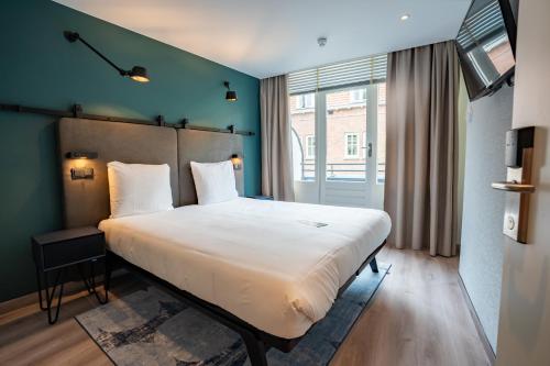 a bedroom with a large white bed and a window at Hotel Kontakt der Kontinenten in Soesterberg