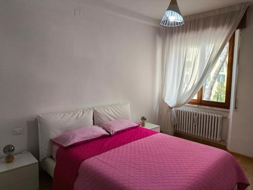 - une chambre avec un lit avec des draps roses et une fenêtre dans l'établissement Casa vacanze Ovidio, à Sulmona