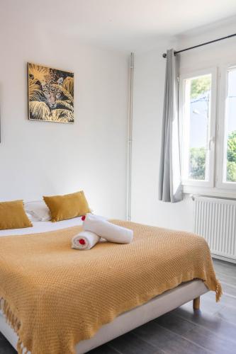 - une chambre blanche avec un lit et une couverture jaune dans l'établissement VILLA COSYFAMILY PISCINE JACUZZI WIFI 15MIN PLAGE idéal FAMILLE - TopProsConciergerie, à Pérols