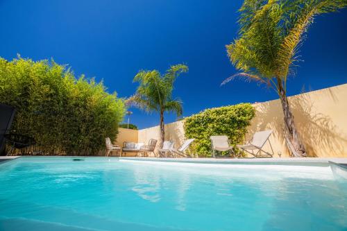 basen z krzesłami i palmami w obiekcie VILLA COSYFAMILY PISCINE WIFI 15MIN PLAGE idéal FAMILLE - TopProsConciergerie w mieście Pérols
