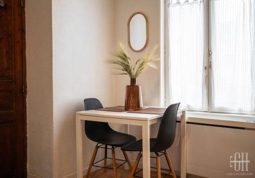 une table avec deux chaises et un vase avec une plante dans l'établissement Le Magnolia - Hôpital Bretonneau, à Tours