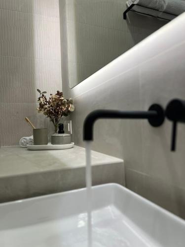 a bathroom with a sink and a faucet and flowers at Oikiaegina in Aegina Town