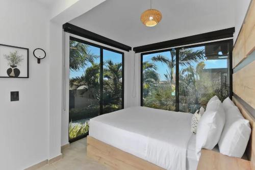 une chambre avec un grand lit blanc et de grandes fenêtres dans l'établissement Bocobay Zen Garden Villa, à Noord