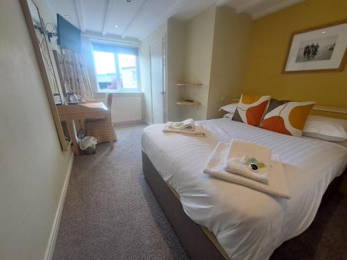 a bedroom with a large white bed with towels on it at The Countryman’s Inn in Hunton