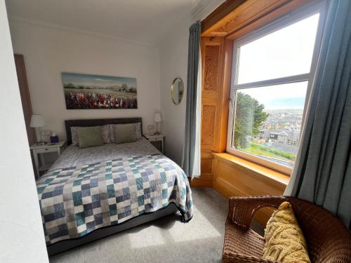 a bedroom with a bed and a large window at Morven Guest House Carnoustie in Carnoustie