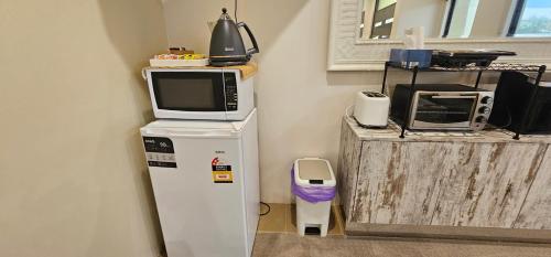 a microwave sitting on top of a refrigerator at Beachside Bliss 1BR Mindarie in Mindarie