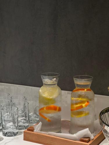 two vases filled with water and glasses on a table at Piazza Epigraph in Batumi