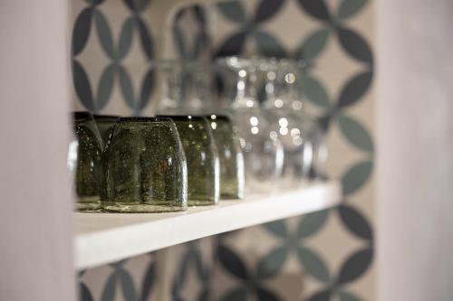 a shelf with green glass vases on it at Olive & Ivy Guesthouse in Canillas de Aceituno