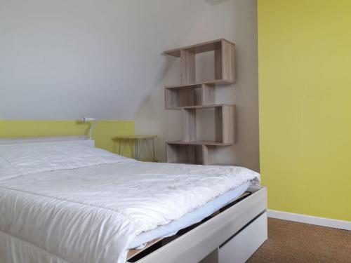 a bedroom with a white bed and wooden shelves at Maison de vacances à Névez Des Lys d'Océan in Névez