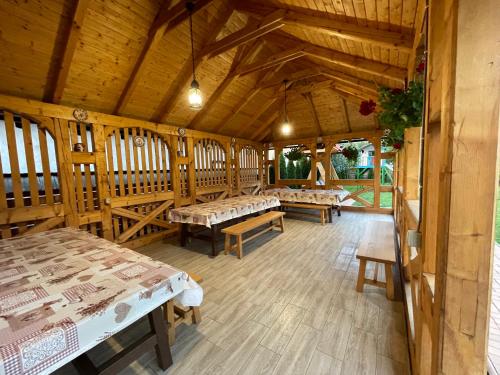 a room with tables and benches in a wooden building at Pensiunea Valea Muntelui in Bîrsana