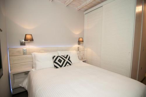 a bedroom with a white bed with two pillows at Nephelis Heritage House in Moúdhros
