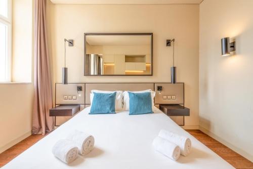 a bedroom with a large white bed with blue pillows at GuestReady - Time Out 105 in Lisbon
