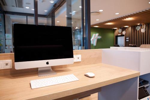 a computer monitor and a keyboard and mouse on a desk at Holiday Inn Berlin City East Side by IHG in Berlin