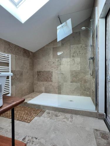 une douche avec une porte vitrée dans une salle de bain dans l'établissement Au Pré de Karine, à Cunèges