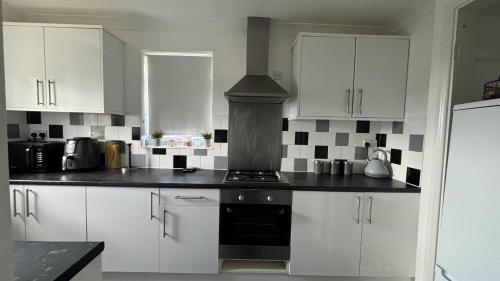 a kitchen with white cabinets and a stove at Romford Cozy Retreat in Romford
