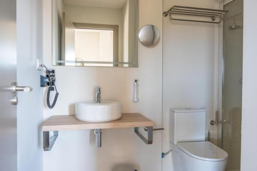 a bathroom with a sink and a toilet and a mirror at L'Alcor Aparthotel in Alicante