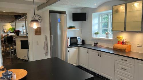a kitchen with white cabinets and a black counter top at Staudeengen et dejlig sted med fred og ro in Ålestrup