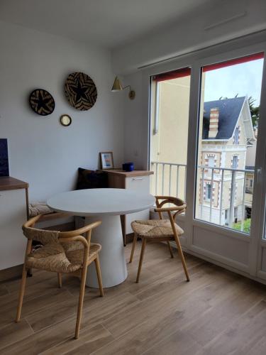 un salon avec une table et des chaises et une fenêtre dans l'établissement Appartement cocon Royan plage, à Royan