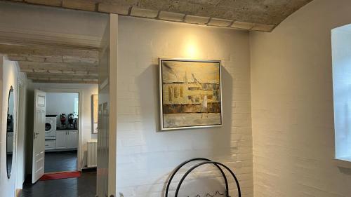 a room with a painting on the wall and a chair at Staudeengen et dejlig sted med fred og ro in Ålestrup