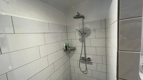 a white tiled shower with a shower head in a bathroom at Staudeengen et dejlig sted med fred og ro in Ålestrup