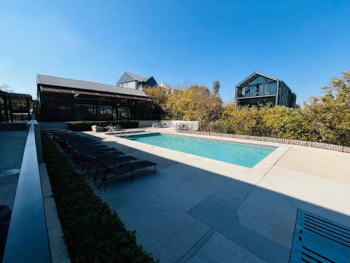 einen Pool mit Stühlen neben einem Gebäude in der Unterkunft 13 Elizabeth Place - Beautiful 2 bedroom unit next to Kyalami Racetrack with free WiFi - swimming pool gym and restaurant - Perfect for a small family in Midrand Waterfall in Midrand