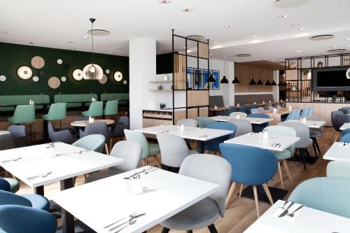 a restaurant with white tables and blue chairs at Holiday Inn Berlin City East Side by IHG in Berlin