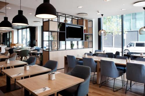 a restaurant with tables and chairs and a flat screen tv at Holiday Inn Berlin City East Side by IHG in Berlin