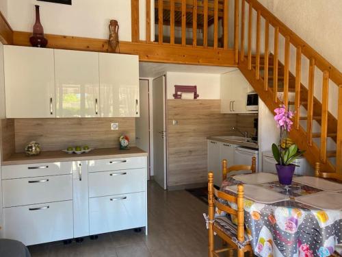 une cuisine avec des placards blancs, une table et un escalier dans l'établissement Villa 5 pers climatisée terrasse et parking proche plage - V0264, à Vias