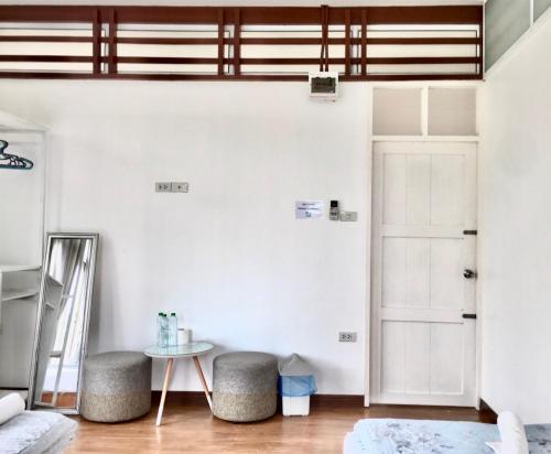 a room with a mirror and two stools and a door at Thirty Tree Garden House in Chumphon