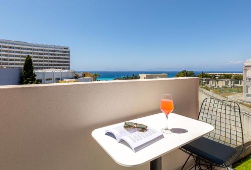 a glass of wine and a book on a table on a balcony at Rhodes Island View in Ixia
